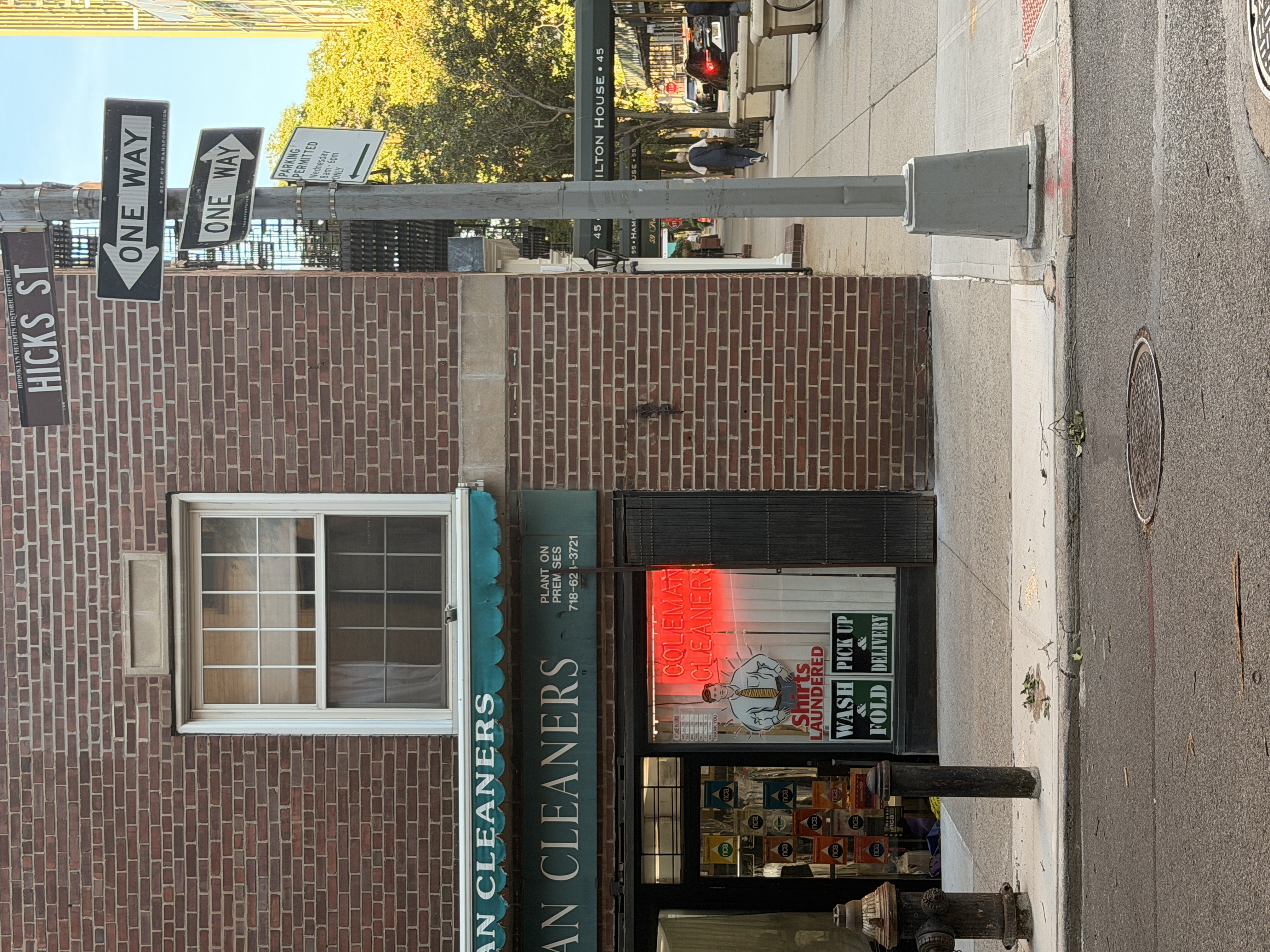 Brooklyn Heights corner cleaners beneath one-way signs on Hicks St
